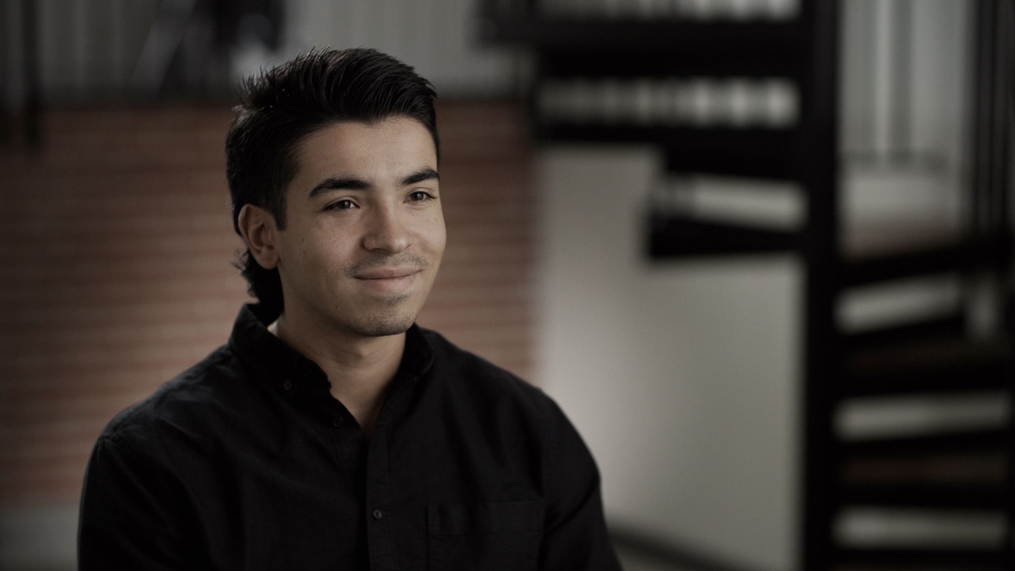 Daniel Pelaez in a black button-down, smiling softly